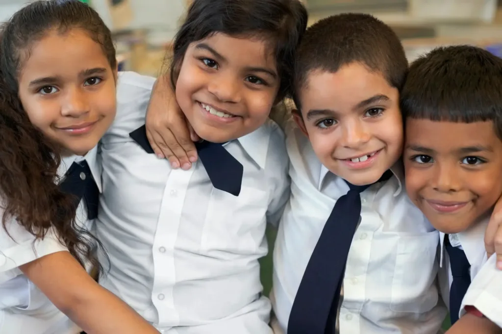 Children in school uniforms smiling and posing for a picture